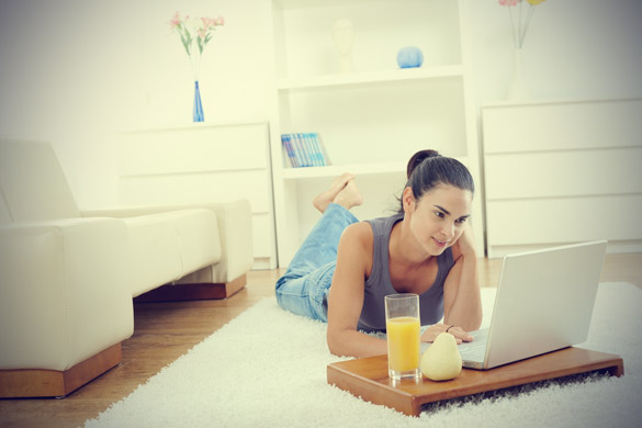 Happy-woman-lying-on-floor-at-home-and-working-on-laptop-computer